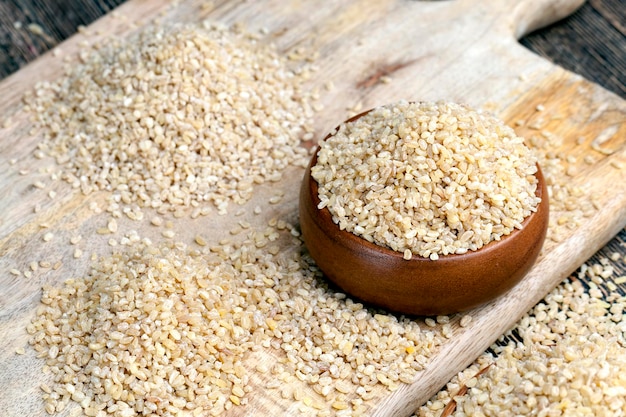 Surowa kasza bulgur, która się nie gotuje, duża ilość zbóż na drewnianym stole, kasza bulgur jest zrobiona z ziarna pszenicy
