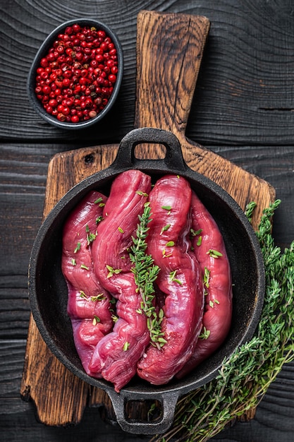 Surowa Polędwica Z Baraniny Filet Mięso, Polędwica Jagnięca Na Rustykalnej Patelni Z Tymiankiem. Czarne Drewniane Tło. Widok Z Góry.