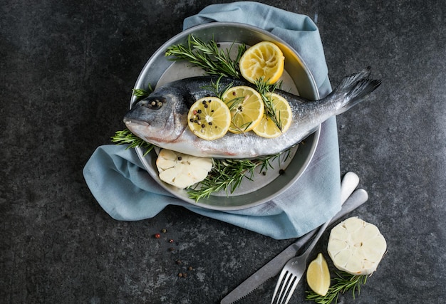 Surowa ryba dorado z przyprawami Dorado i składnikami do gotowania na stole