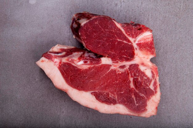Surowe mięso pokrojone z tłustym stekiem z kości w sklepie mięsnym na kamieniu pośrodku