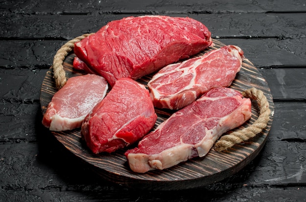 Surowe mięso Steki wołowe i wieprzowe na drewnianej tacy