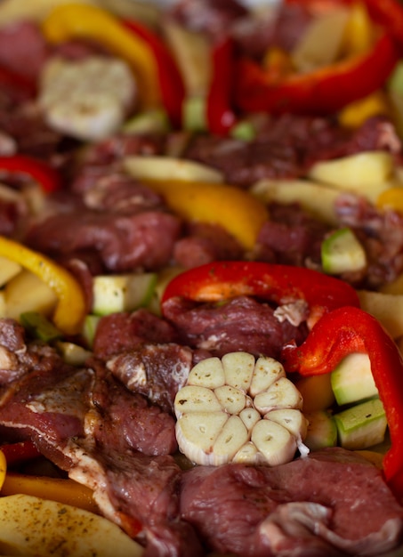 Zdjęcie surowe mięso wołowe z surowymi warzywami: cukinia, czosnek, czerwona i żółta papryka z naturalnymi przyprawami i ziołami