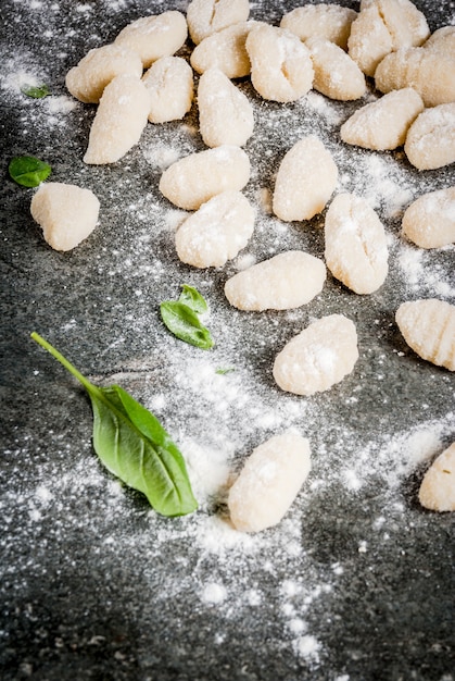 Surowe niegotowane domowe gnocchi ziemniaczane z mąką, tartym parmezanem, bazylią i sosem pesto. Na betonowym szarym