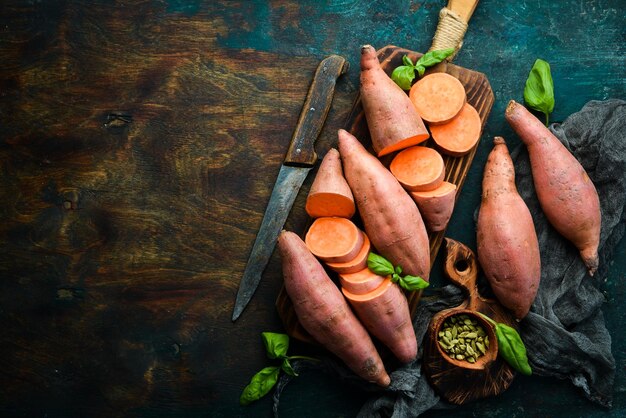 Surowe organiczne słodkie ziemniaki na drewnianym tle Żywność dietetyczna Widok z góry