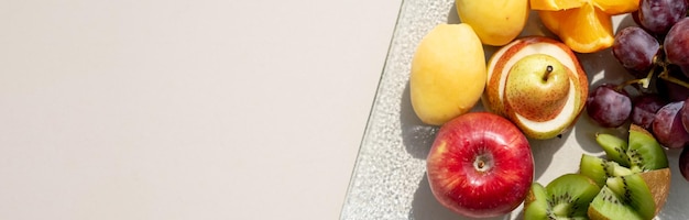 Surowe owoce jagody półmisek pomarańcze kiwi grejpfruty winogrona gruszki jabłka na talerzu na białym stole