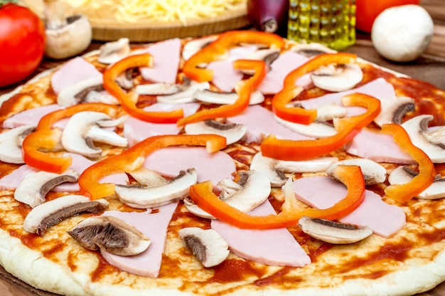 Surowe pokrojone składniki do pizzy na cieście do pizzy z bliska