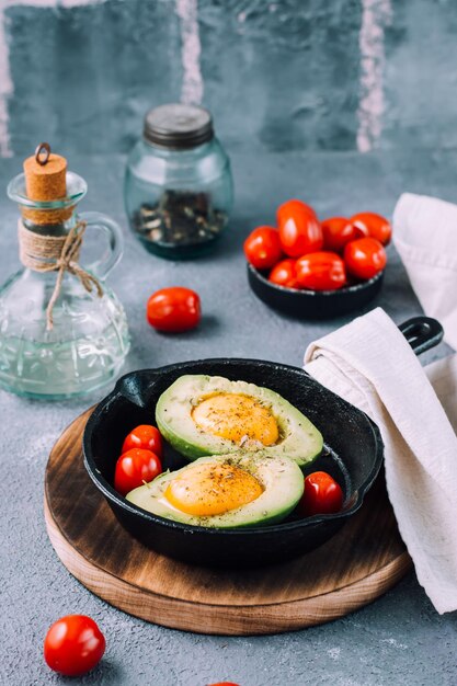 Surowe Połówki Awokado, Gotowe Do Pieczenia, Nadziewane Jajkiem I Pomidorkami Koktajlowymi Na Patelni Na Stole. Zdrowe Odżywianie. Dieta Flexitarian. Widok Pionowy