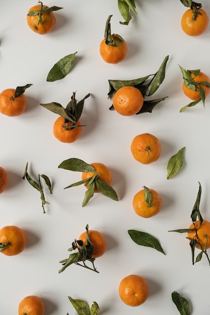 Surowe pomarańcze, owoce mandarynki z zielonym wzorem liści na białym