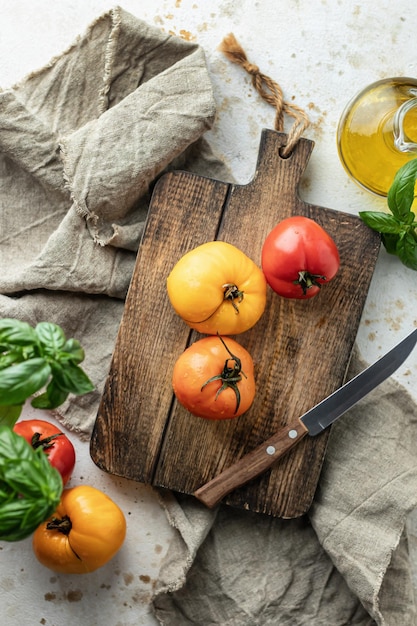 Surowe pomidory i nóż na drewnianej desce do krojenia otoczone składnikami wokół Widok z góry