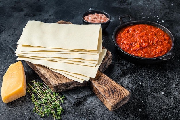 Surowe Różne składniki do gotowania włoskiej lasagne na kuchennym stole. Czarne tło. Widok z góry.