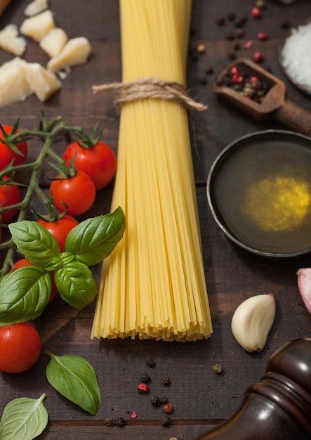 Surowe spaghetti z parmezanem i bazylią pomidorową z czosnkiem i oliwą na drewnianym tle z solą i pieprzem Makro