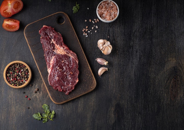 Surowe świeże mięso Przyprawa Ribeye Steak i świeży pomidor na drewnianym tle