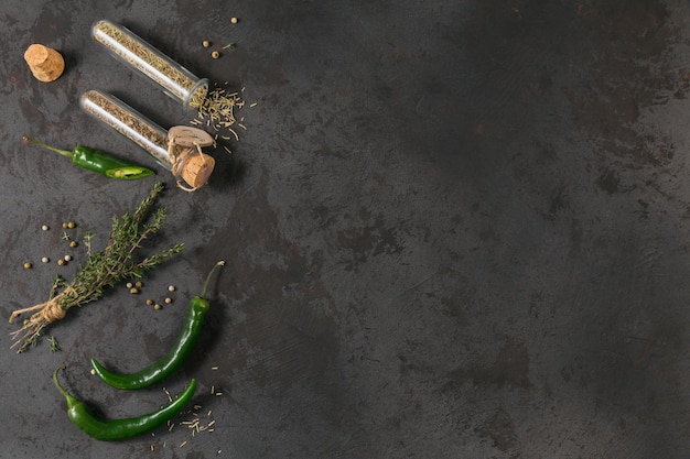 Surowy świeży organiczny zielony pieprz chili i różne przyprawy na czarnym tle Rozmaryn i bazylia w szklanych kolbach Przyprawy do ramki żywności