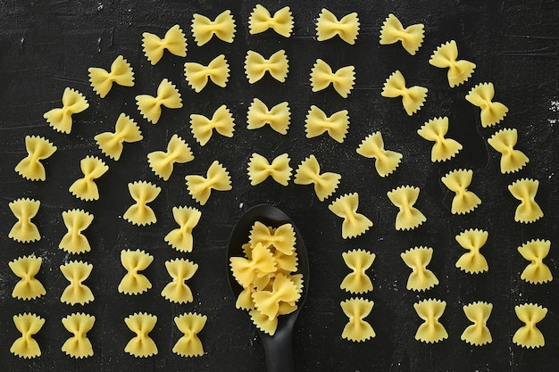 Zdjęcie surowy wzór farfalle na czarnym tle górny widok składnika kuchni włoskiej