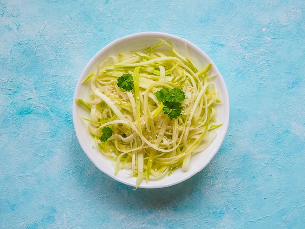 Surowy zucchini makaron na błękita stole, kopii przestrzeń