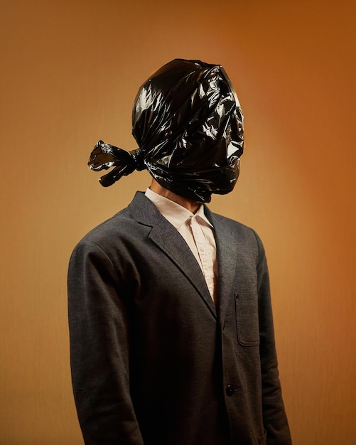 Surrealistyczna koncepcja - mężczyzna w garniturze z czarną plastikową torbą na śmieci na głowie. zanieczyszczenie przyrody