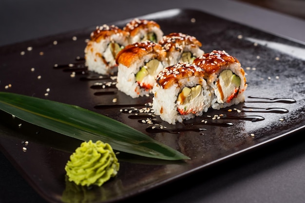 Sushi california roll z sosem i sezamem na czarnym talerzu