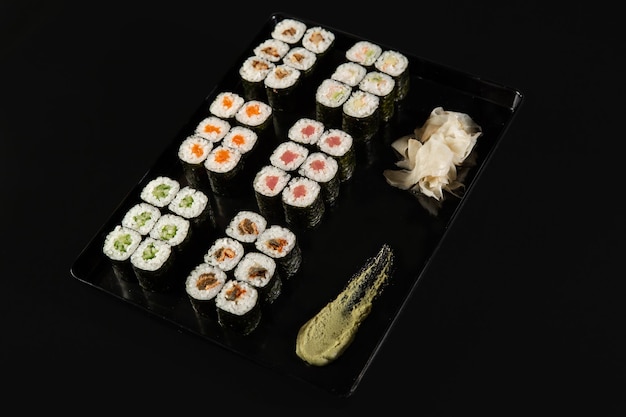 Sushi i krewetki smażone w czosnku na kamiennym talerzu z czarnym tłem