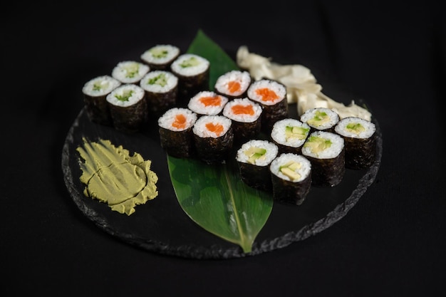 Sushi i krewetki smażone w czosnku na kamiennym talerzu z czarnym tłem