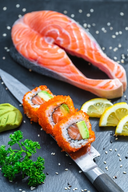 Sushi podawane na japońskim nożu na czarnym talerzu z łupków