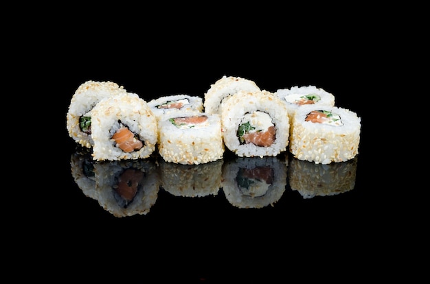 Sushi roll philadelphia w sezamie z łososiem na czarnym tle
