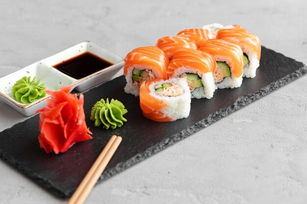 Sushi roll pokryte świeżym łososiem serwowane na talerzu z bliska