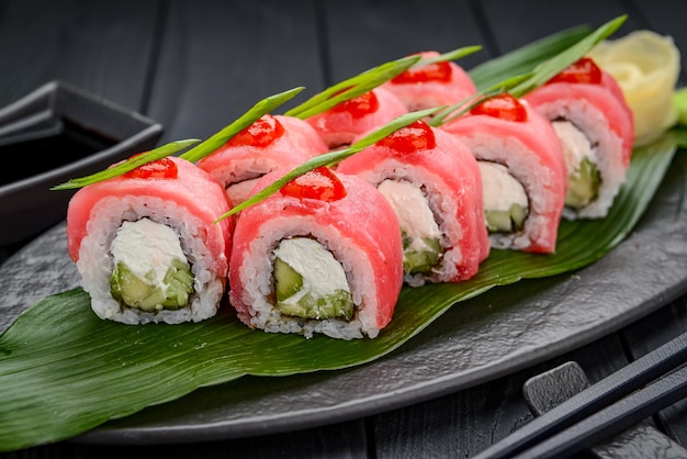 Sushi roll smok z tuńczykiem Tradycyjne pyszne świeże sushi roll ustawione na czarnym tle Menu sushi Japońska kuchnia restauracja Azjatyckie jedzenie