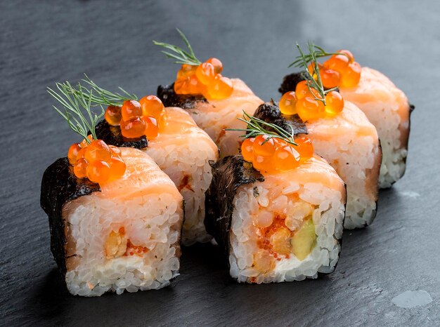 Sushi roll z łososiem i kawiorem na czarnym tle