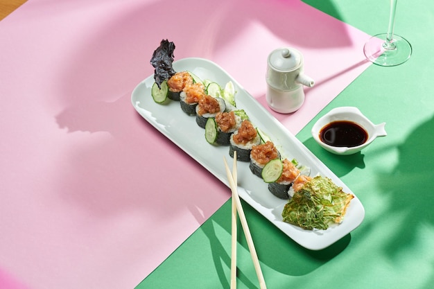 Sushi roll z tuńczykiem i ogórkiem w talerzu z jasnym tłem. Selektywne skupienie, twarde cienie