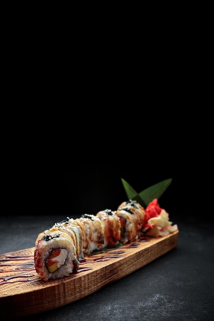Sushi roll Złoty smok z węgorzem łososiem tobiko i serkiem na drewnianej desce