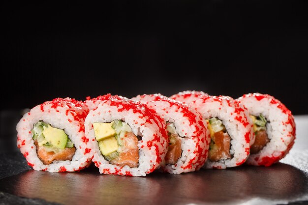 Sushi Rolls z awokado, ogórkiem i łososiem w środku na czarno