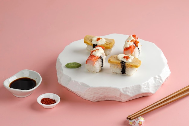 Sushi Tamago i Crabstick Roll na białym orientalnym talerzu różowym tle