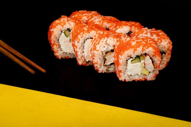 Sushi Ustawia Uramaki, ser Philadelphia na ciemnym, odblaskowym tle.