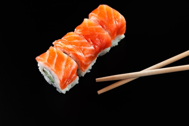 Sushi Z Czerwoną Rybą Na Czarnym Tle Z Bambusowymi Pałeczkami