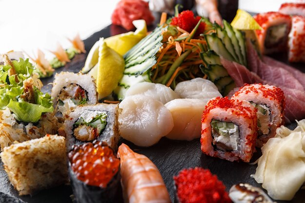 Sushi zestaw bułek z przegrzebkami i warzywami, na czarnym kamieniu