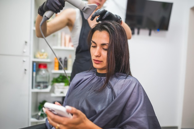 Suszenie długich ciemnych włosów suszarką do włosówprofesjonalny fryzjer suszy włosy klientki w salonie fryzura uroda pielęgnacja włosów usługi modowe