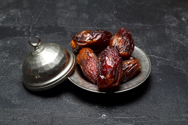 Suszone daktyle na drewnianym stole w srebrnych naczyniach z bliska Skład suszonych daktyli w naczyniu z ramadanu
