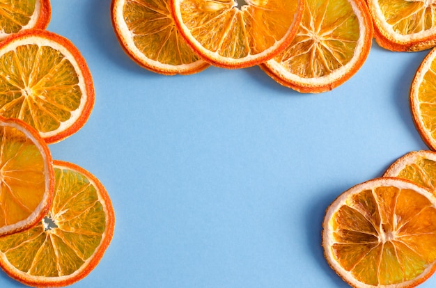 Suszone plasterki pomarańczy owoców cytrusowych na jasnoniebieskim tle. Domowy naturalny aromat.