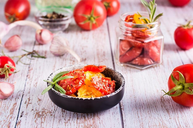 Suszone pomidory z przyprawami i czosnkiem w misce oraz świeże warzywa na stole Domowa przekąska