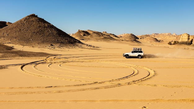 SUV jadący przez piasek czarno-białej pustyni Egiptu