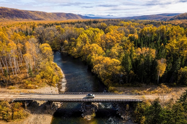 Zdjęcie suv na drewnianym moście nad małą halną rzeką jesień las