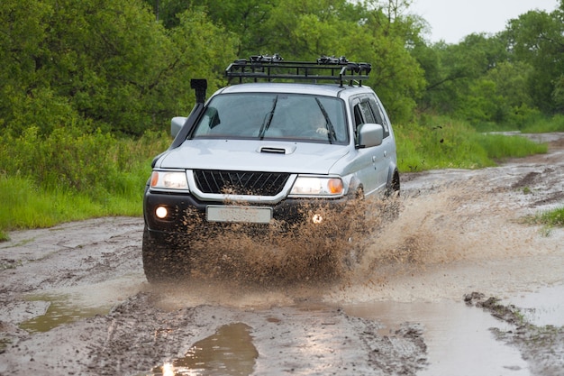 SUV poruszający się po wodzie w deszczu, powodując wiele rozprysków