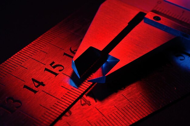 Zdjęcie suwmiarka i metalowe linijki oświetlone na czerwono i niebiesko