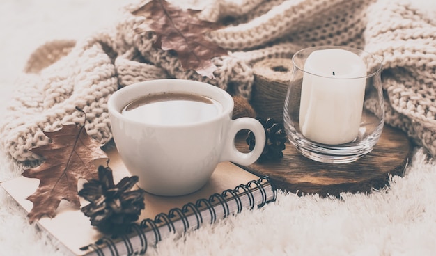 Zdjęcie swetry i filiżanka herbaty z notatnikiem, świecą i ubraniami na drutach