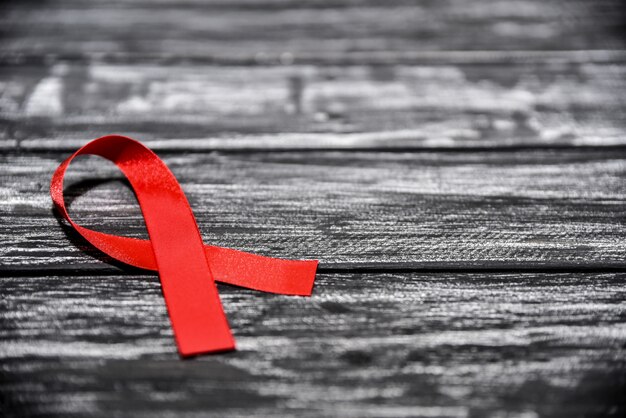 Zdjęcie Świadomość czerwoną wstążką na czarnym drewnianym tle na światowy dzień aids, światowy dzień szczepień na aids. selektywne skupienie.