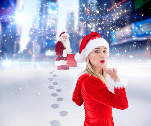 Świąteczna blondynka dmuchająca buziaka przed Mikołajem dostarczającym prezenty w mieście