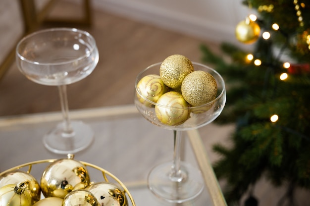 Świąteczna dekoracja, kieliszki do szampana i złote bombki. Noworoczne wnętrze z choinką.