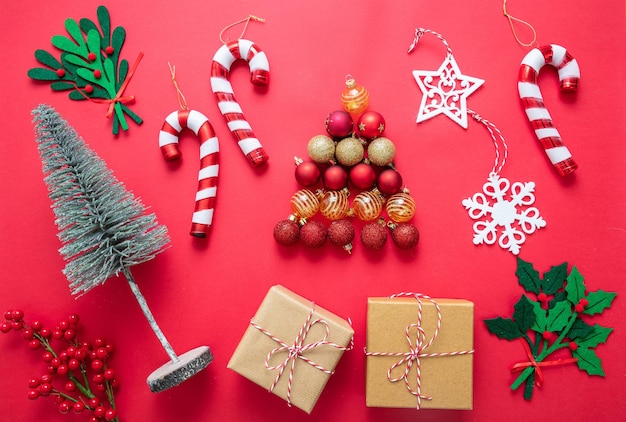 Świąteczna dekoracja płaska na czerwonym tle prezenty kulki i laski cukierkowe