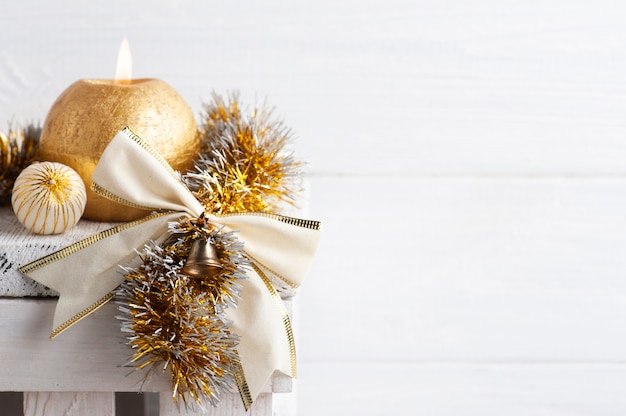 Świąteczna dekoracja w skandynawskim wnętrzu ze złotą kokardką, kulkami i zapaloną świecą. Skopiuj miejsce na powitanie