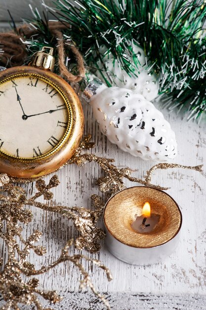 Świąteczna dekoracja w skandynawskim wnętrzu ze złotym zegarem, zabawkami i zapaloną świecą. Skopiuj miejsce na powitanie